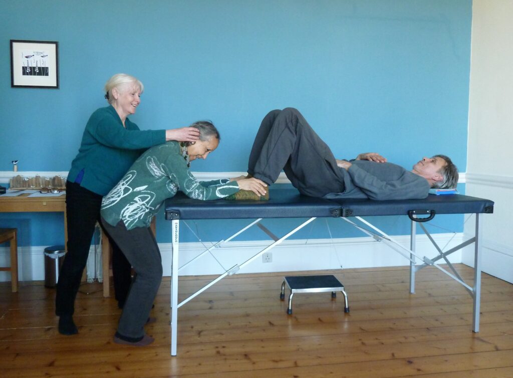 Photo of trainee being helped to put hands on someone lying on a table